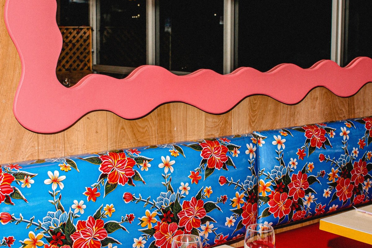Colorful dining booth with floral blue vinyl seating and pink wavy trim against wood paneling