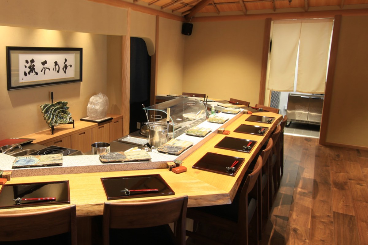 Interior counter dining room with wooden chef's counter, lacquered trays, and chairs