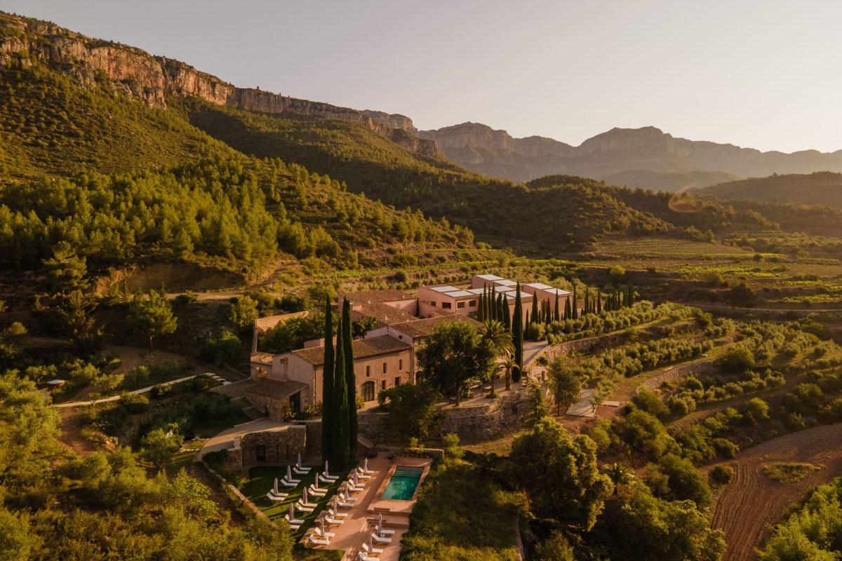 Aerial view of Terra Dominicata hotel estate nestled among green mountains with pool and sun loungers at golden hour