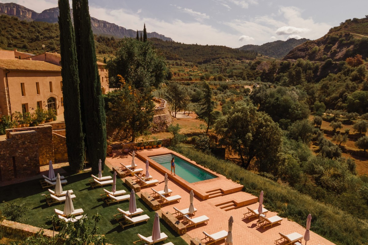 Aerial view of hotel terrace with pool, sun loungers, and cypress trees overlooking valley