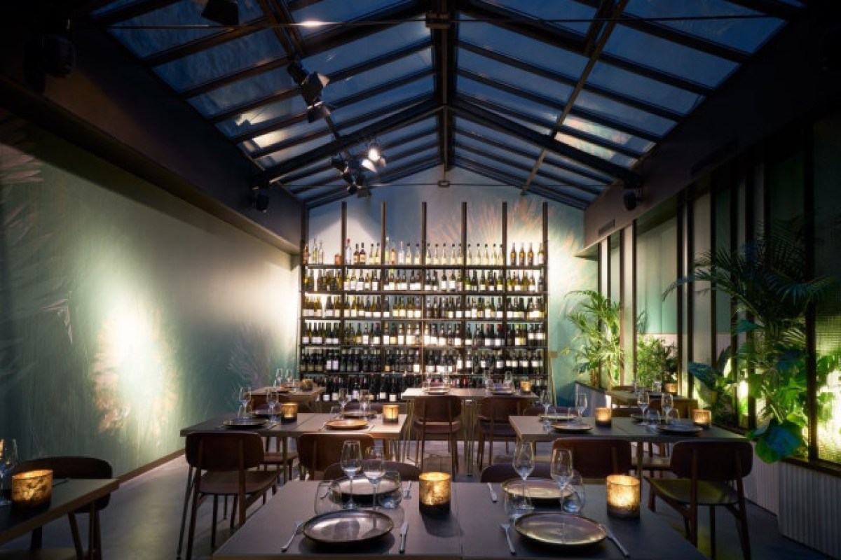 Terra dining room with wine wall shelving, glass roof and set tables lit by candles