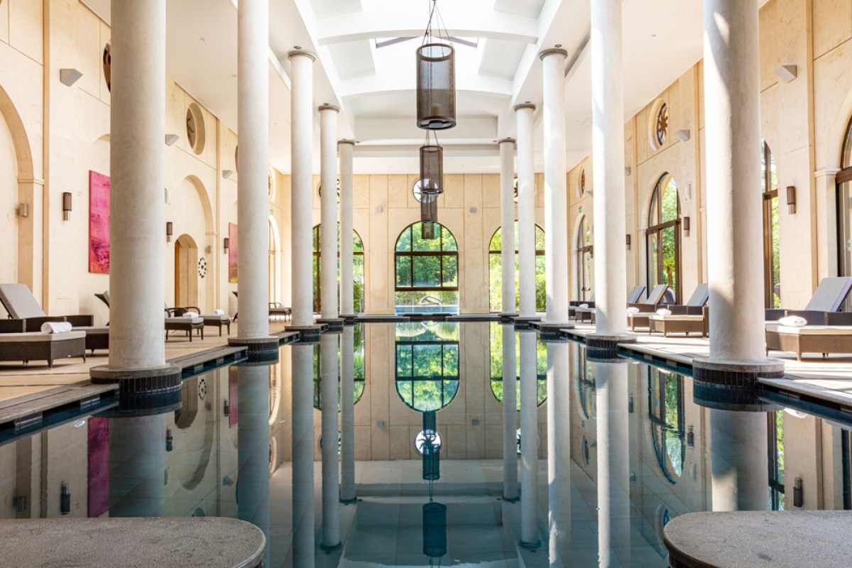 Elegant indoor pool with marble columns, reflections and arched windows at the spa