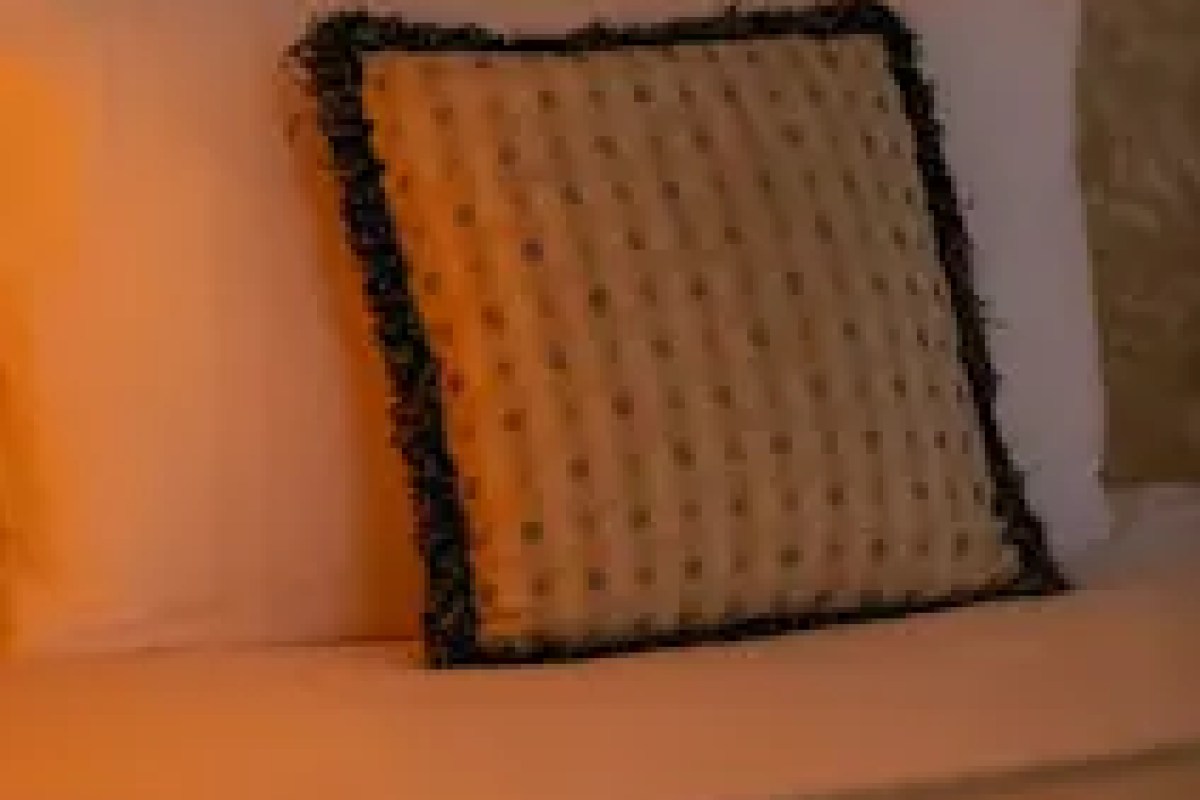 Close-up of a patterned orange and black throw pillow on a hotel bed