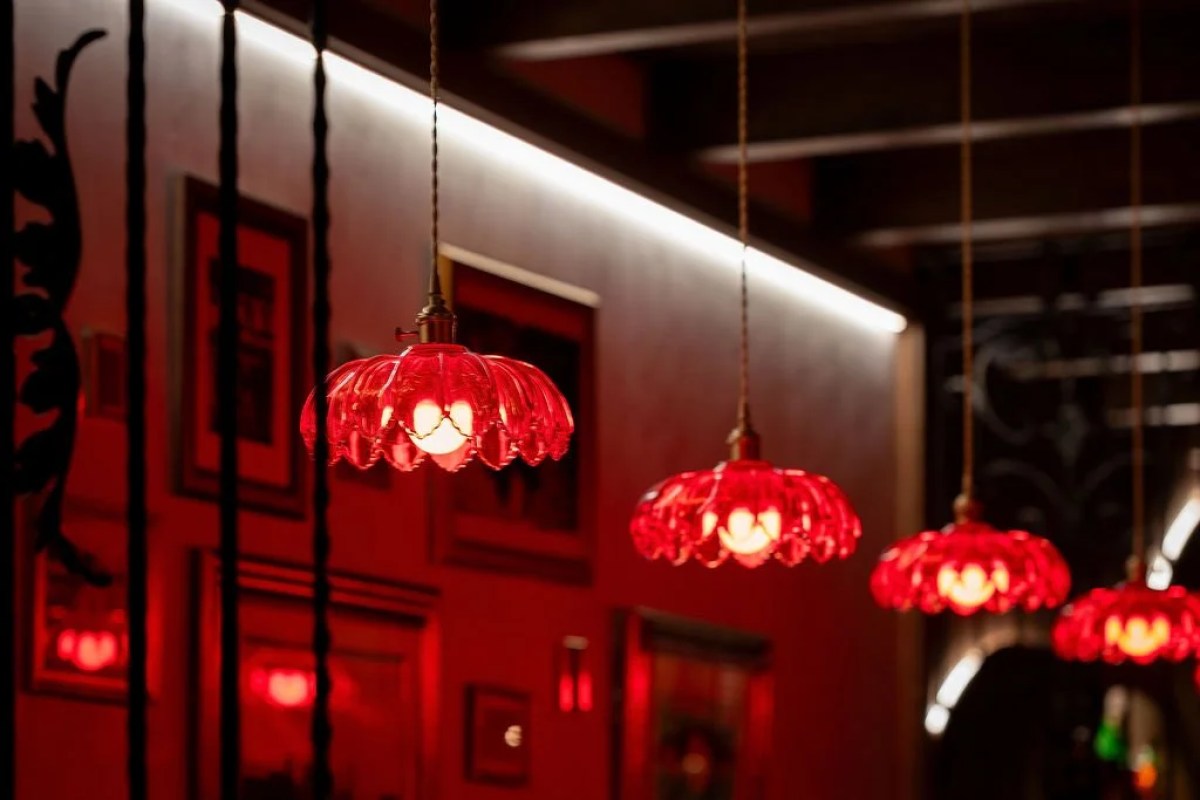 Red glass pendant lamps hanging in a dimly lit dining room with framed pictures on the wall