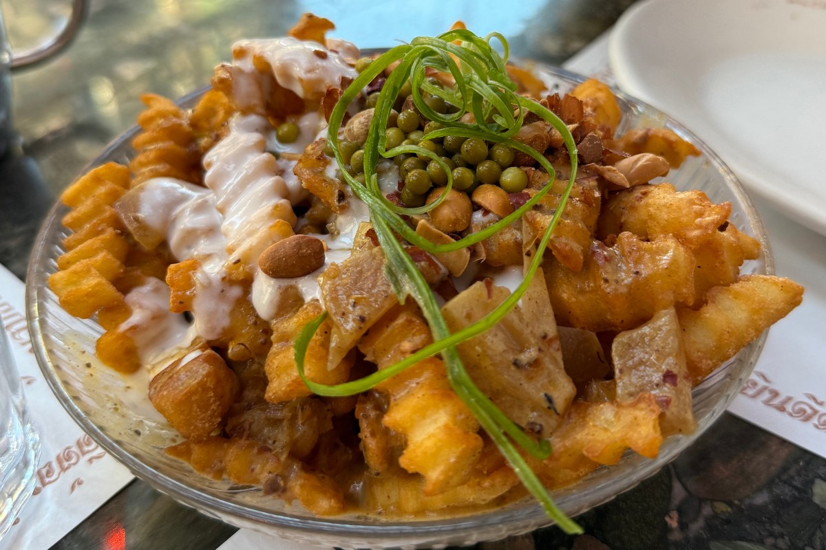 Disco fries dish topped with peas, peanuts, sauce and scallion curls, served on a table at Thai Diner.