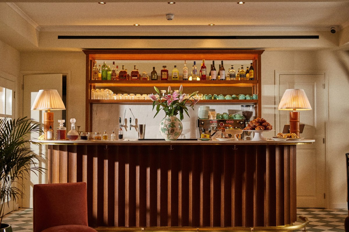 The Bar at The Agora Hotel, a wooden counter with lamps, bottles and flowers in warm evening light