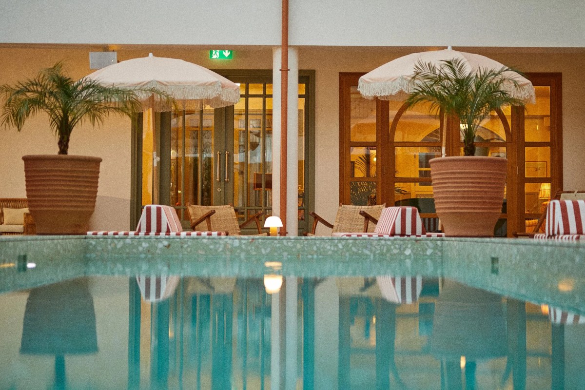 The saltwater courtyard pool at The Agora Hotel, framed by potted palms, parasols and the arcaded walls of the former market