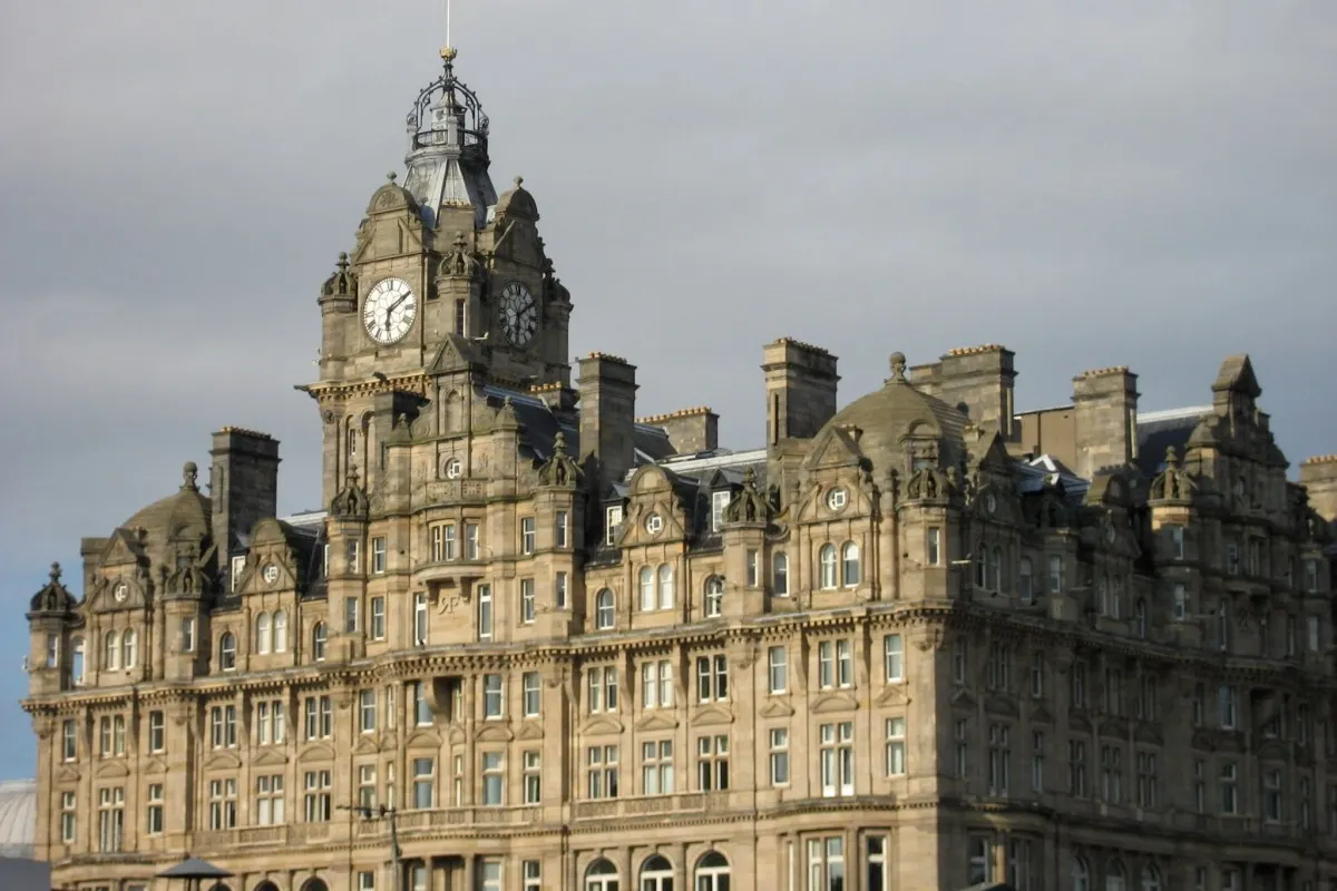 Close-up of The Balmoral Hotel's sandstone façade and clock tower under a cloudy sky