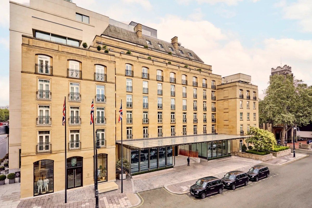 Aerial view of The Berkeley hotel's sandstone facade with glass canopy entrance, flags, and black cabs parked outside
