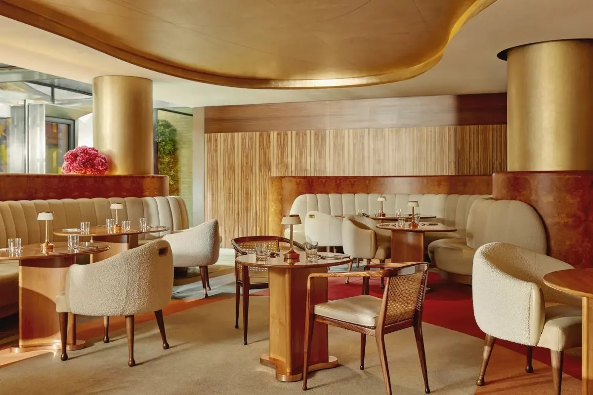 Elegant hotel lounge/bar with gold curved ceiling, banquette seating and wooden tables