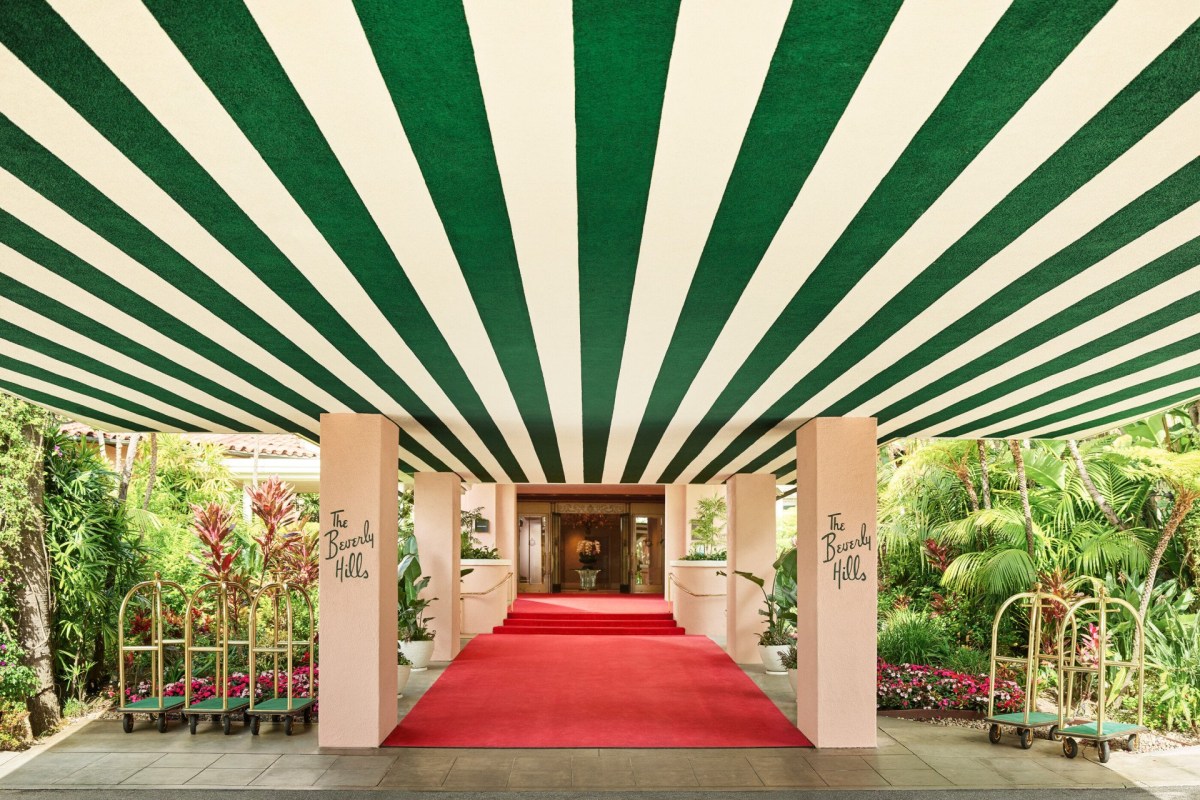 Entrance of The Beverly Hills Hotel with green-and-white striped awning and red carpet leading to lobby doors