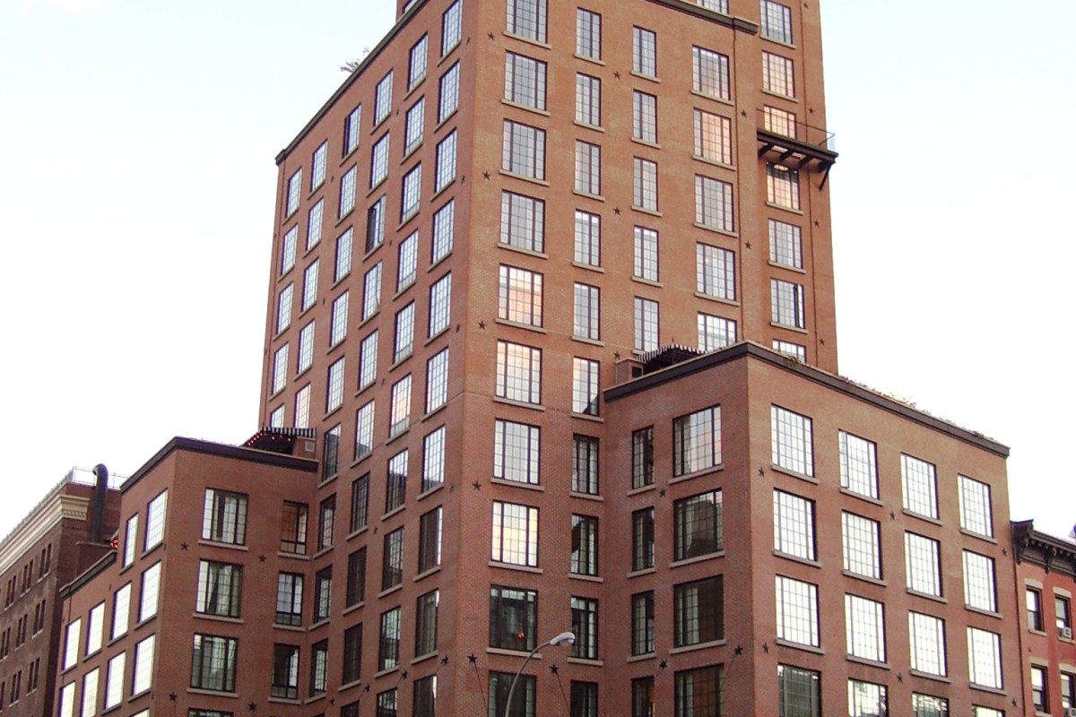 Full view of The Bowery Hotel tower showing brick façade, setbacks, and terraces against the sky