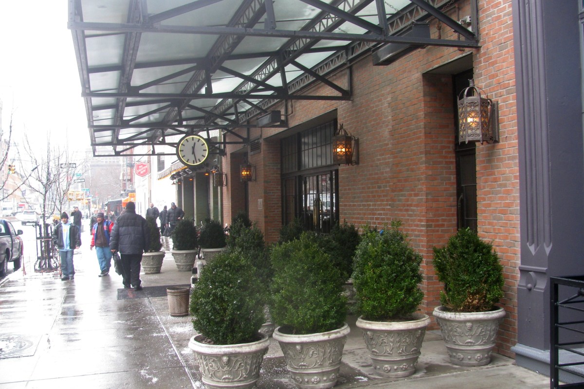 Exterior ground floor entrance of The Bowery Hotel with awning, lanterns, clock, and potted topiaries