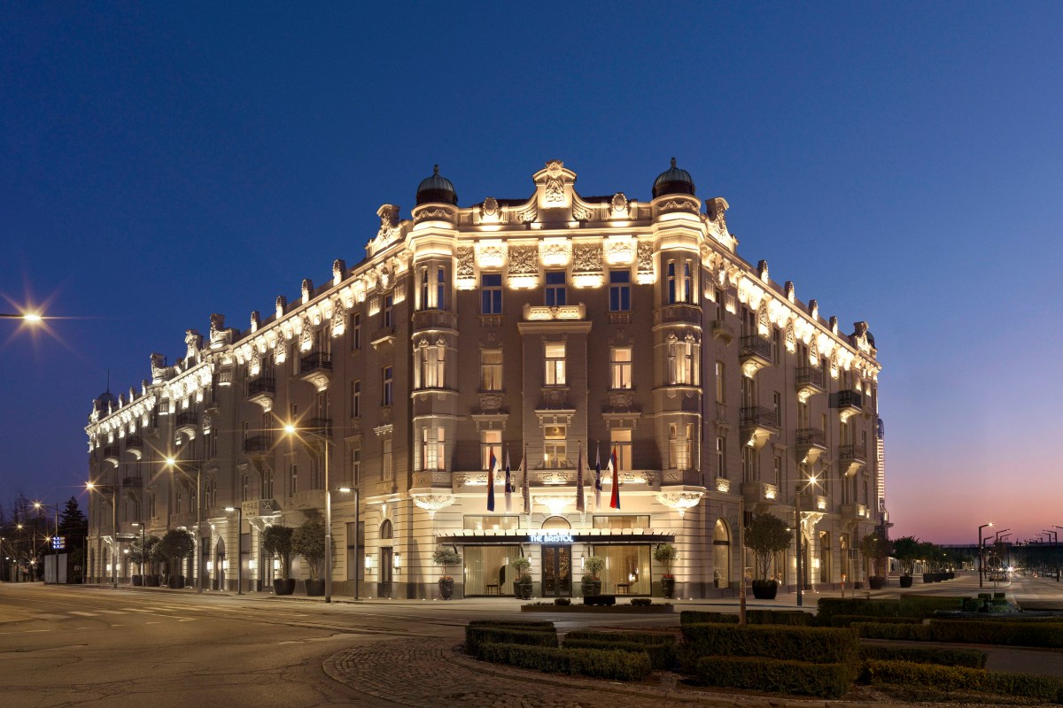 Twilight exterior shot of The Bristol Belgrade hotel's grand corner façade lit up against a dusk sky