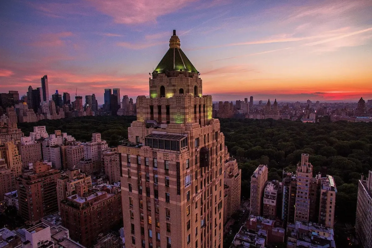 Aerial sunset view of The Carlyle's iconic tower rising above Central Park and the Manhattan skyline
