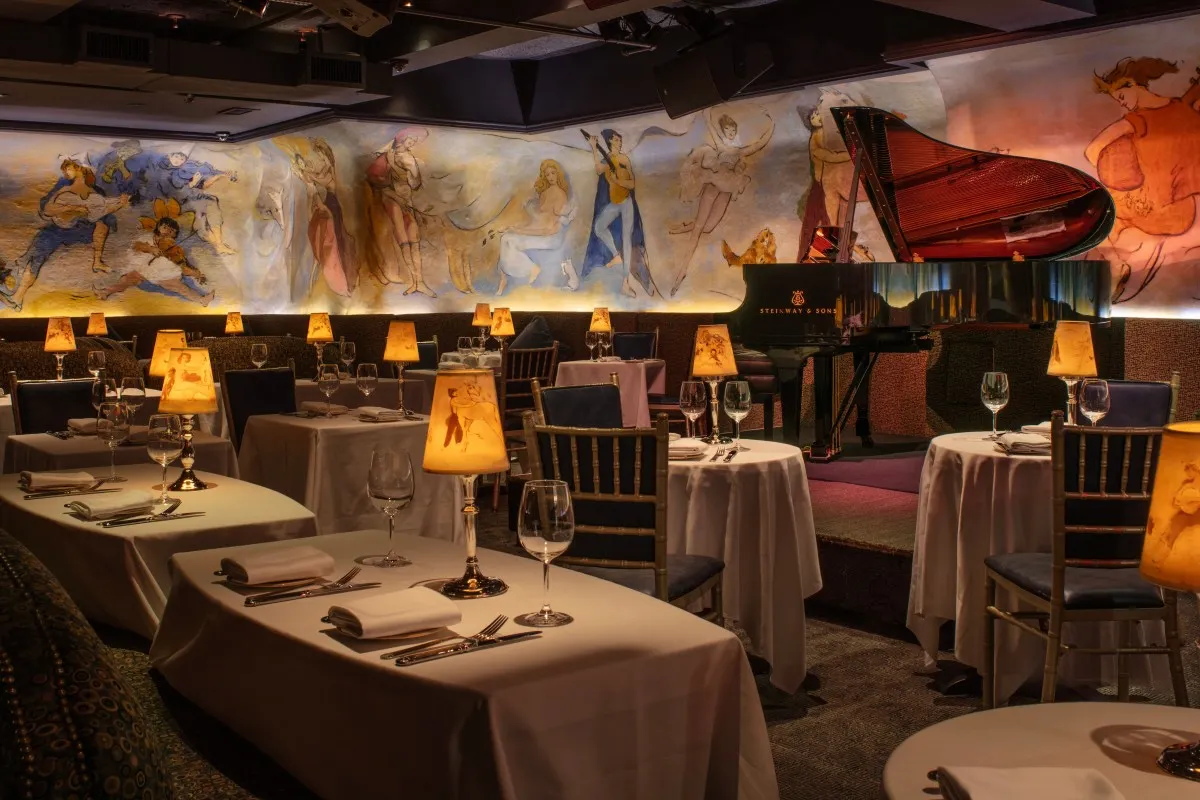 Café Carlyle style lounge with grand piano, murals, and elegant table settings