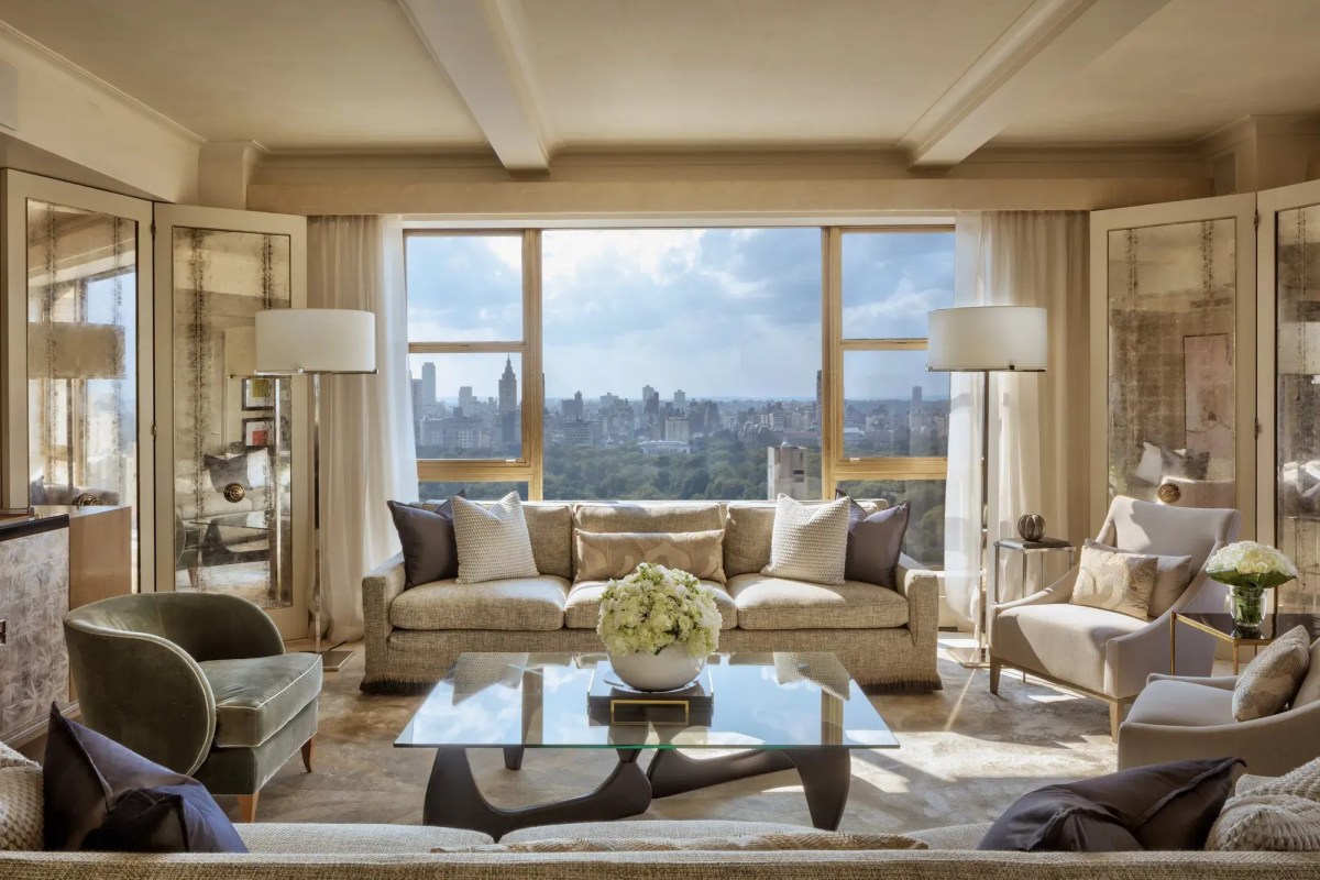 Hotel suite living room with sofas, glass table, and panoramic Central Park skyline view