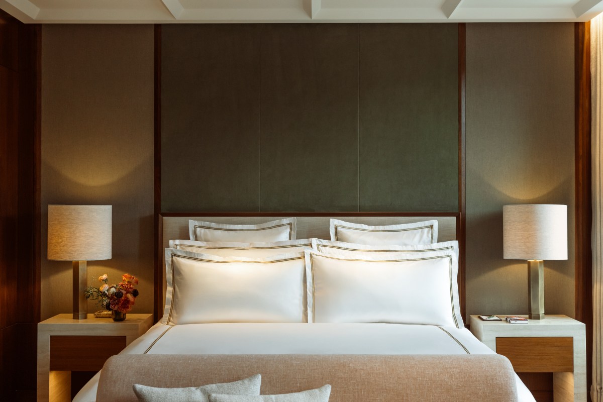 Luxurious hotel bedroom with a large bed, layered white pillows, dark wood headboard and bedside lamps