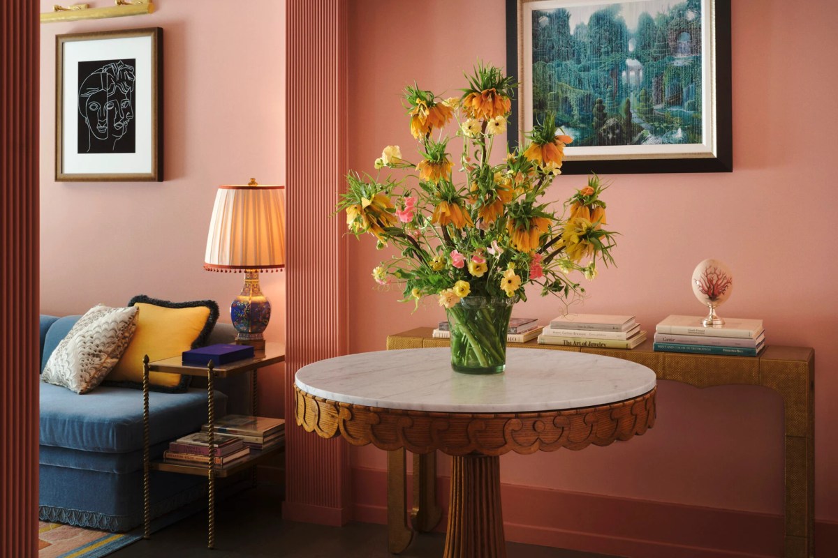 Hotel lounge corner with pink walls, floral arrangement on marble table, and blue sofa
