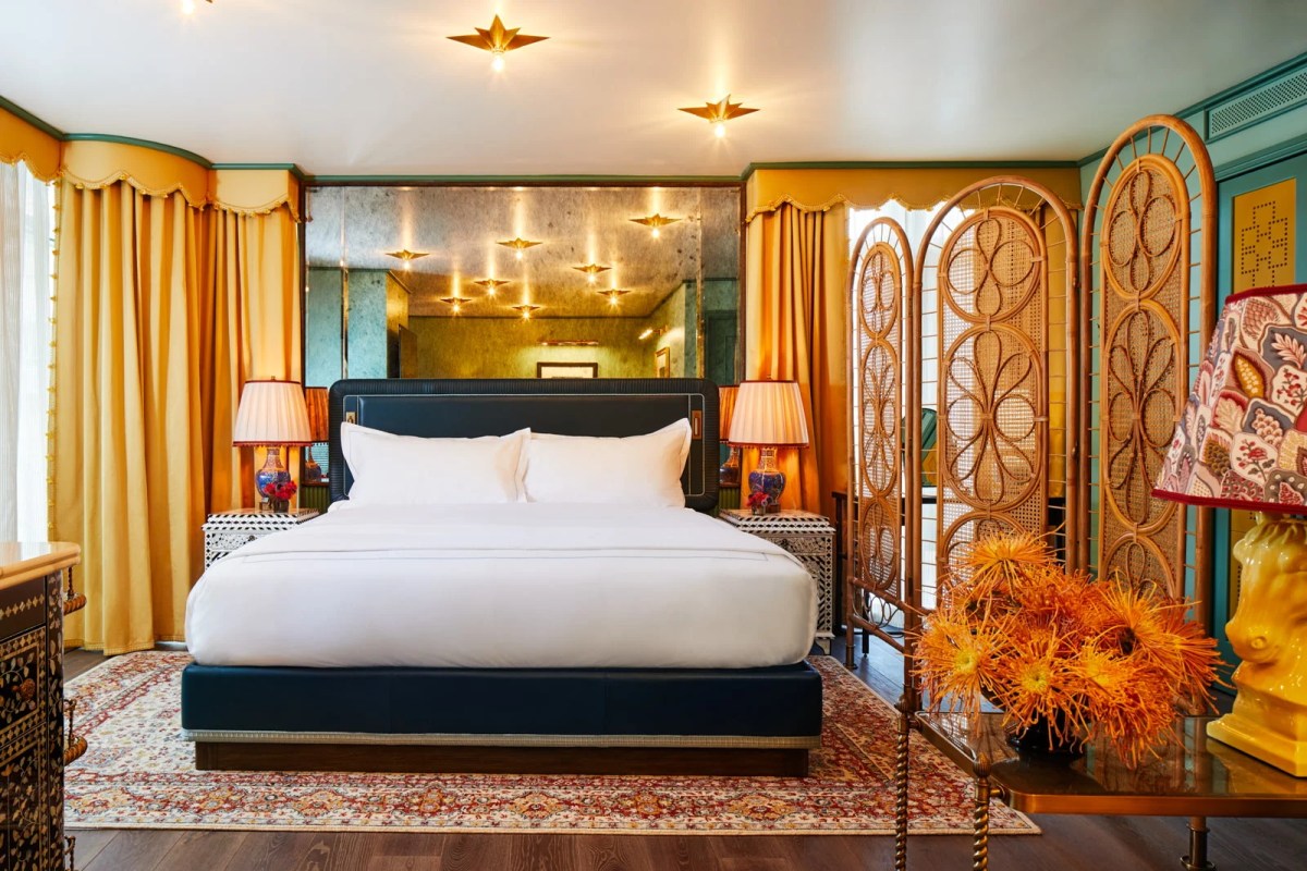 Opulent bedroom with navy bed, gold curtains, rattan screen, and starburst ceiling lights