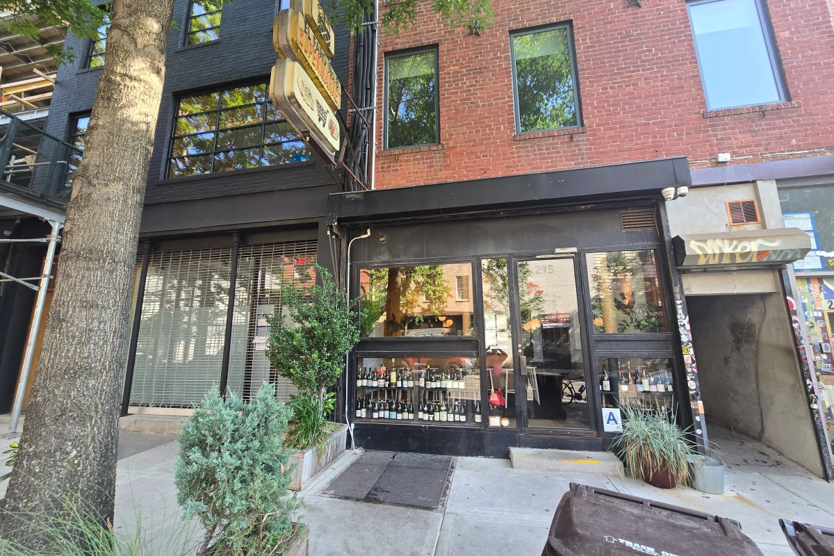 Exterior storefront of The Four Horsemen restaurant with black facade and wine bottles in window, Brooklyn street view