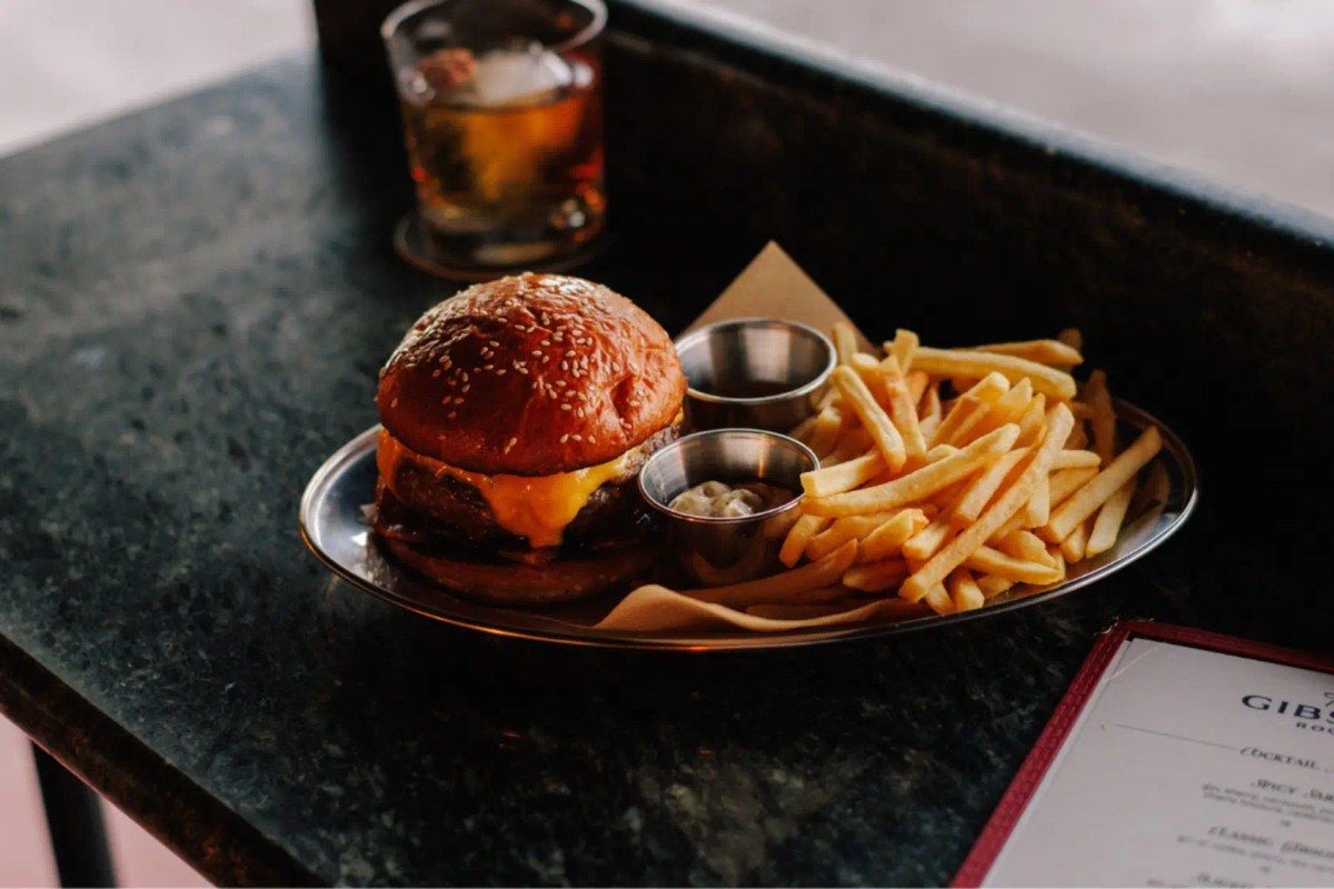 Cheeseburger with sesame bun and french fries on a tray at The Gibson Room
