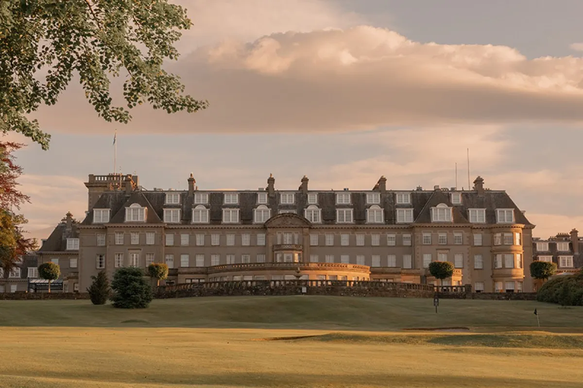 Gleneagles Hotel grand façade at golden hour, viewed across the golf course lawn