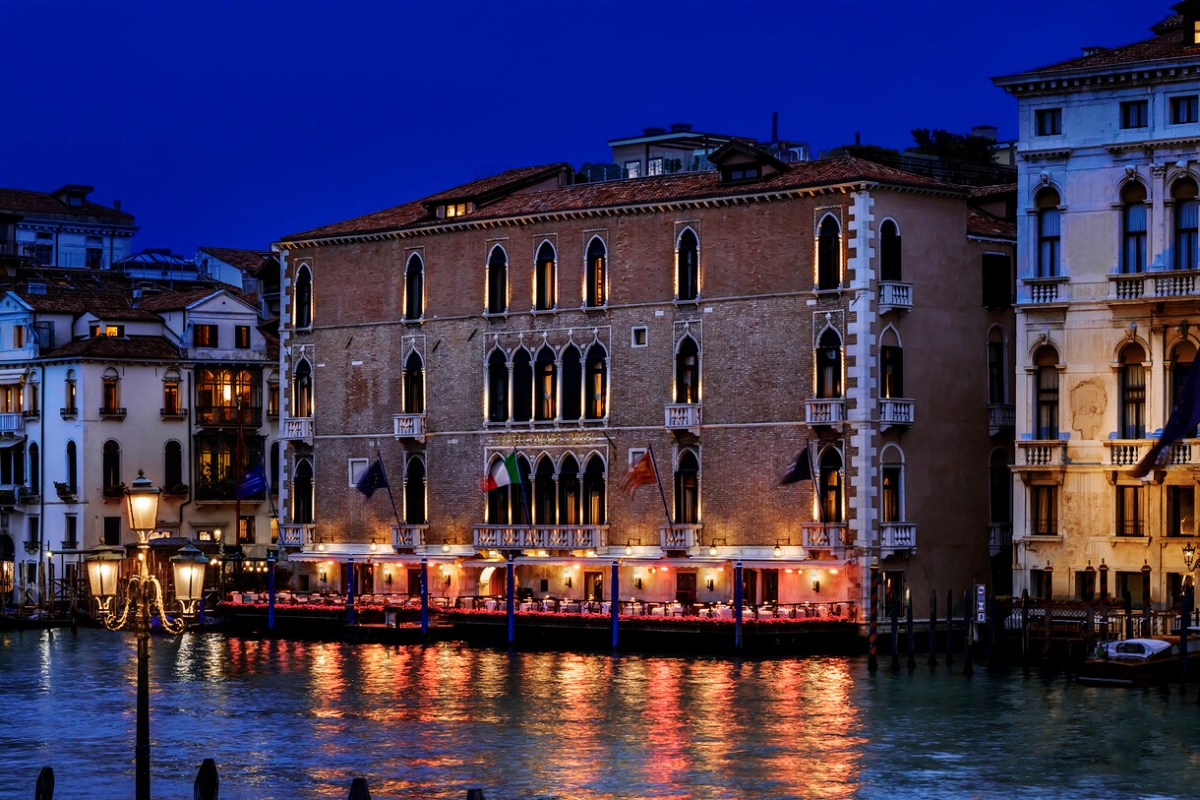 Night view of The Gritti Palace's Gothic façade along the Grand Canal, illuminated windows reflecting on water