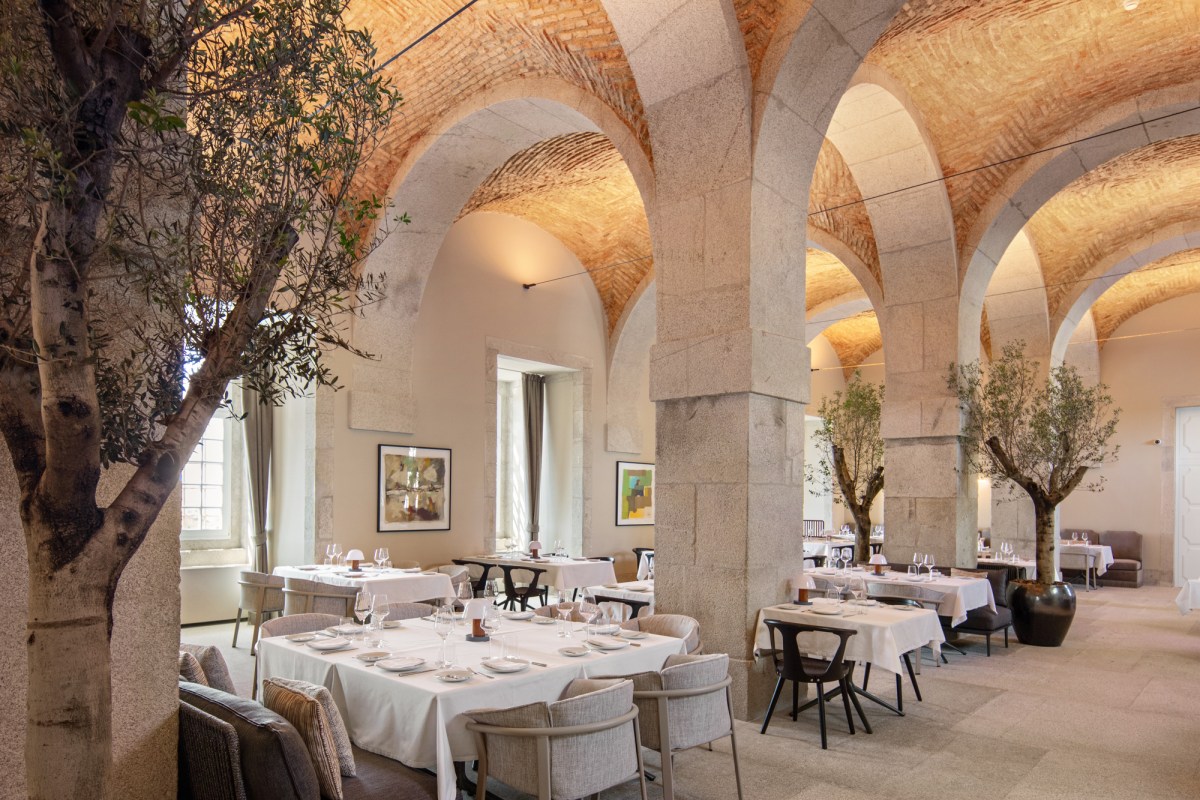 Hotel restaurant with vaulted brick ceilings, stone columns, set tables and olive trees