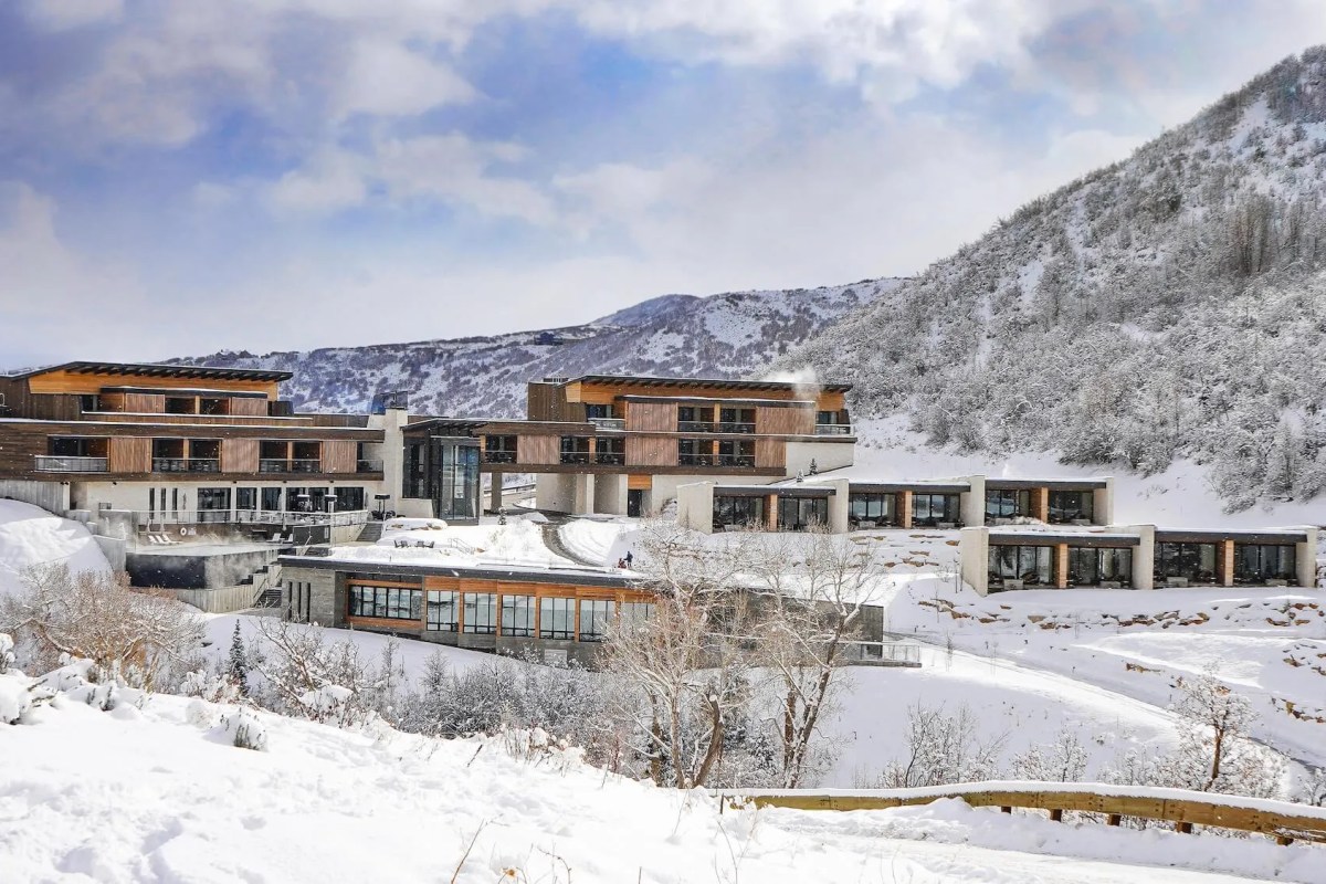 Wide exterior view of The Lodge at Blue Sky's modern wood-and-stone buildings nestled in a snowy mountain landscape.