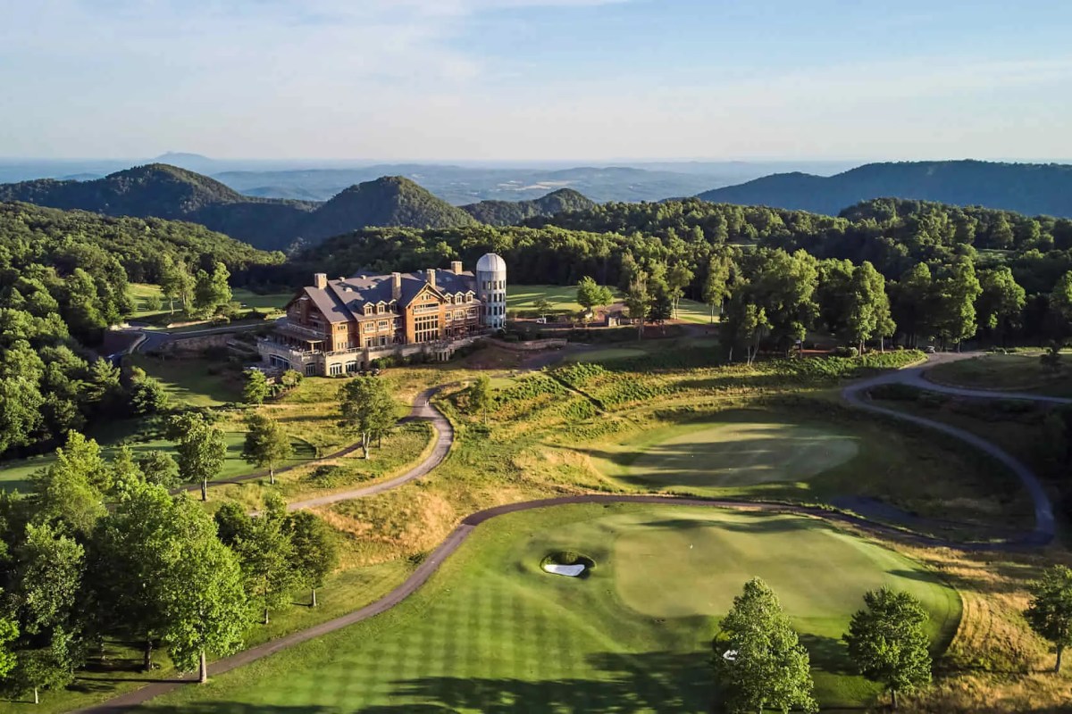 Aerial view of The Lodge at Primland surrounded by golf course and mountains at sunrise