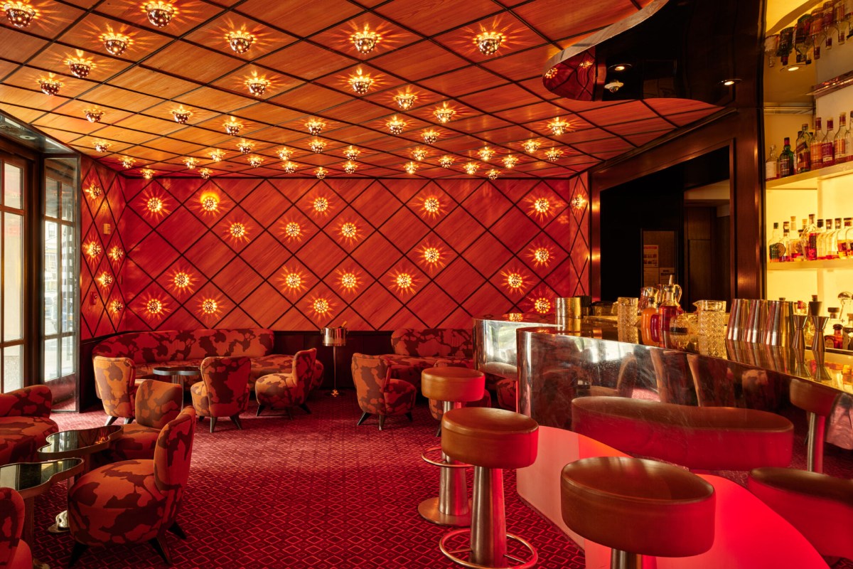 Richly decorated bar lounge with red diamond-patterned walls, round stools, and armchairs at The Mark Hotel.