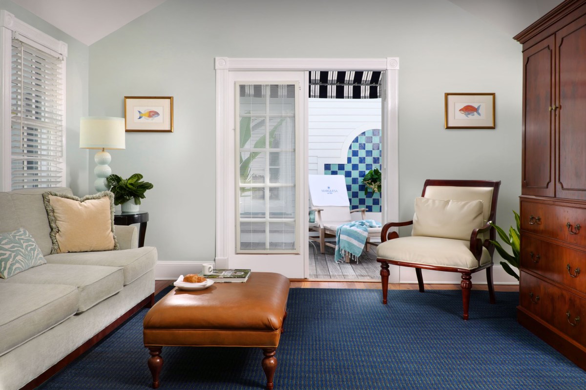 Hotel suite living room with sofa, ottoman, armchair, and doors opening to a private balcony