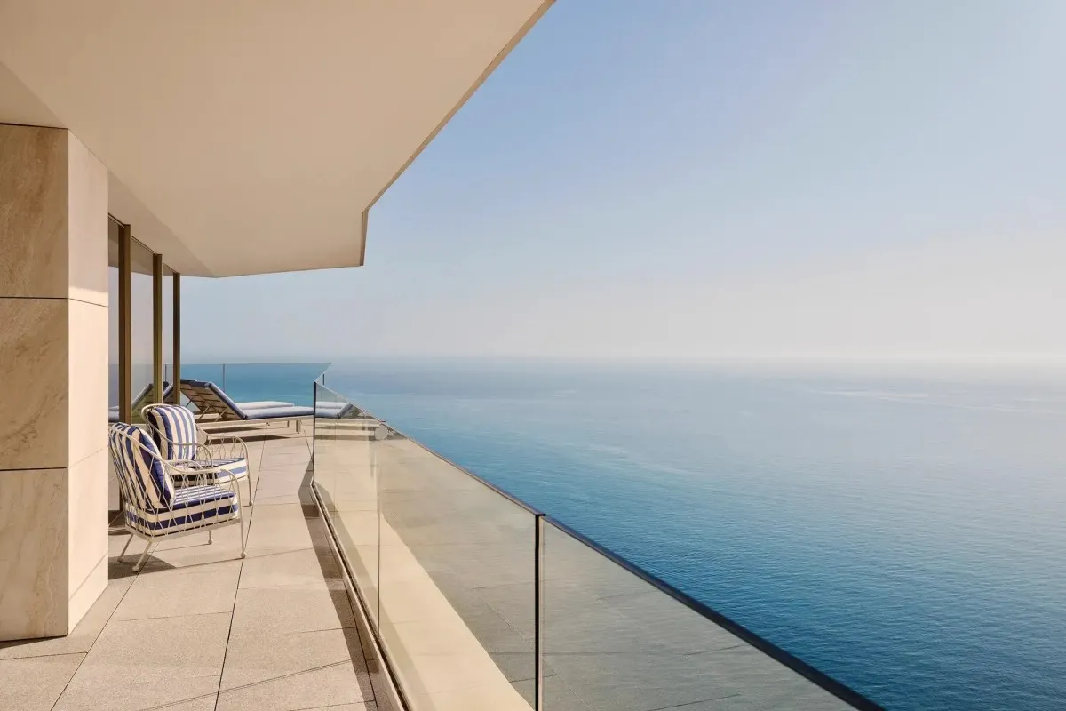 Private room balcony with striped lounge chairs and glass railing overlooking the Mediterranean Sea