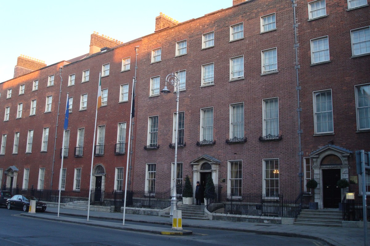 Georgian red-brick facade of The Merrion Hotel with flags, railings and entrance, warm evening light
