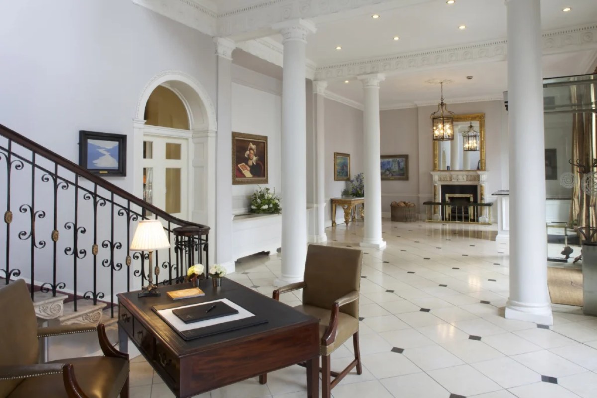 Elegant hotel lobby with marble columns, fireplace, mirror, and antique desk
