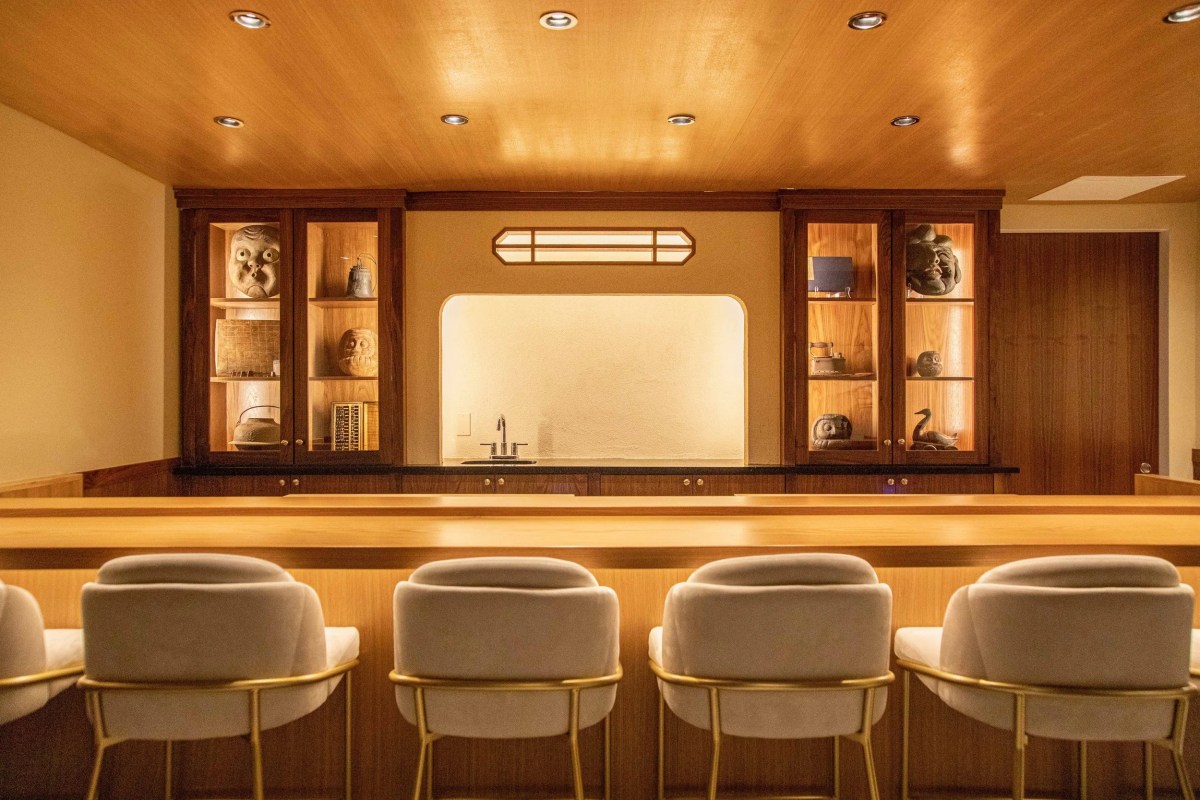 Interior bar area with wood paneling, display cabinets with Japanese objects, and cream bar stools