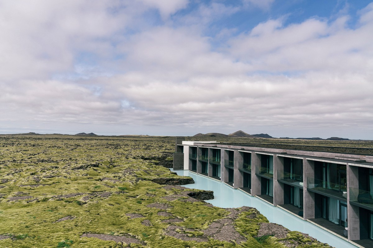 Aerial view of the hotel's long concrete facade built along the lava field with the Blue Lagoon's milky water beside it