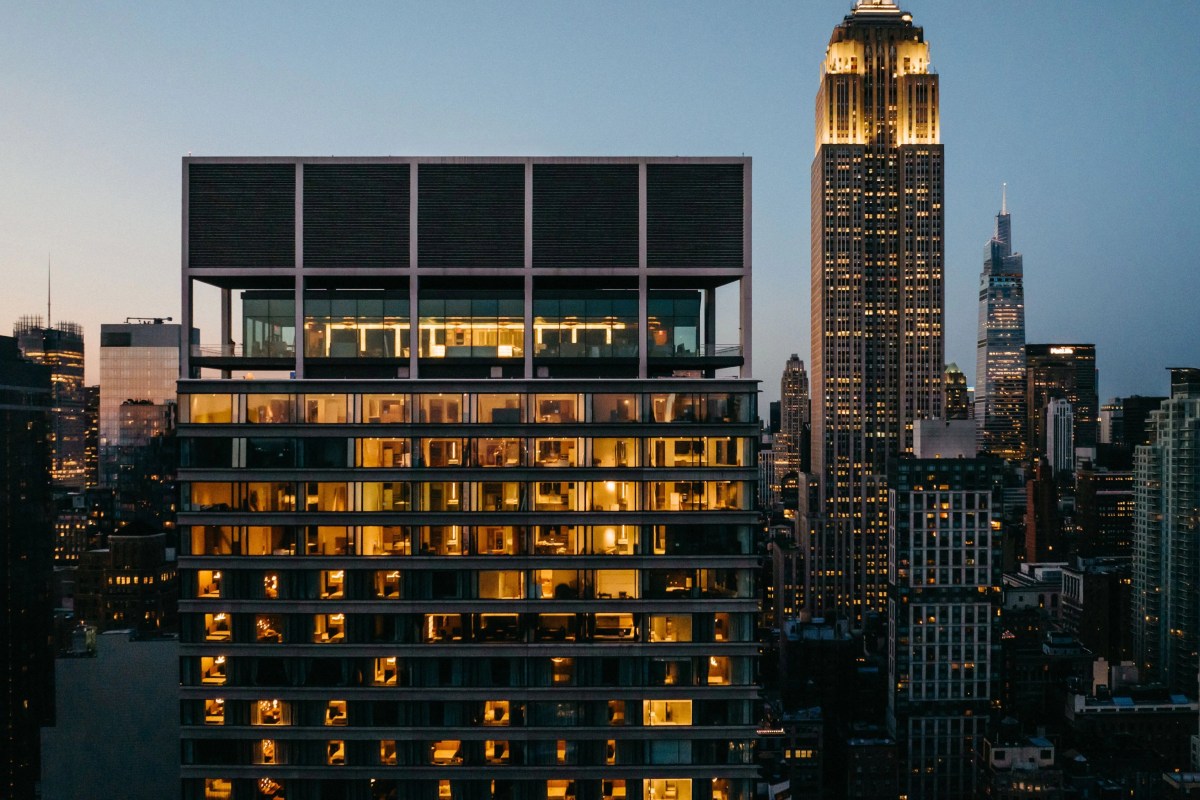 Twilight view of the Ritz-Carlton New York NoMad tower glowing with lit windows, Empire State Building in background