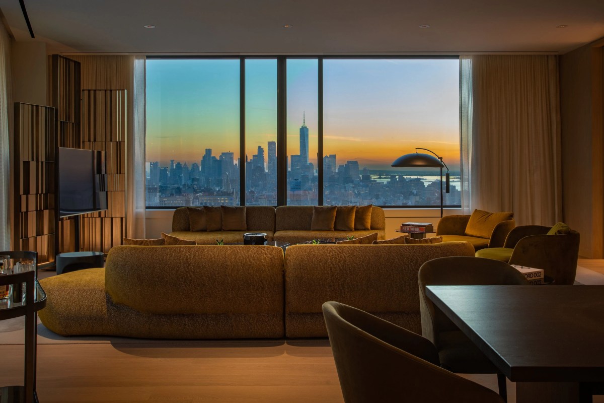 Suite living room with mustard sofas and large window showing sunset city skyline