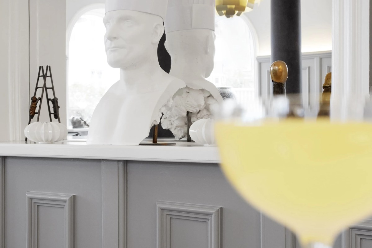 Bar area with white bust sculptures and a blurred yellow cocktail glass in the foreground.