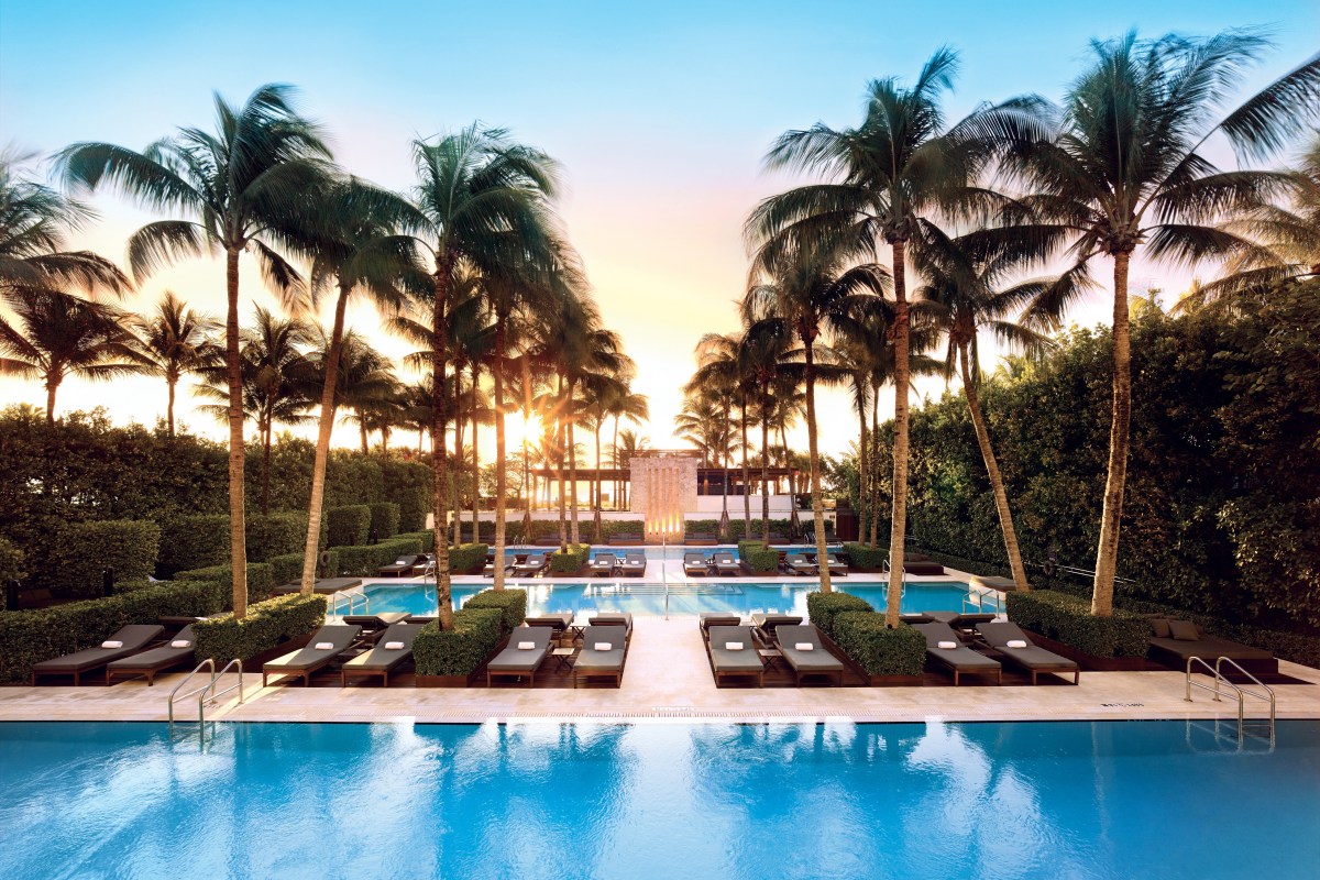 The Setai's resort pools lined with palm trees and lounge chairs at sunset.
