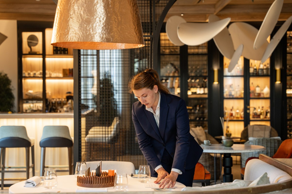 Restaurant interior with staff setting table, bar shelves in background