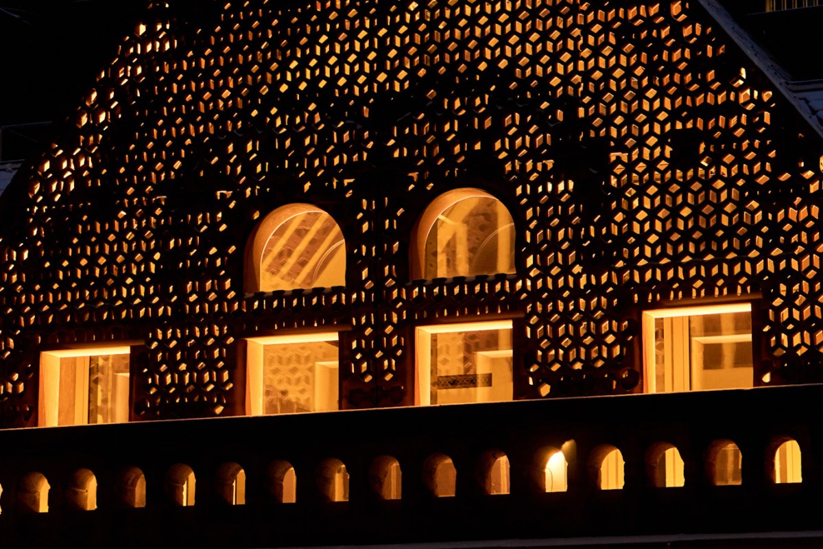 Night view of the hotel's ornate illuminated facade with arched windows and lattice screen