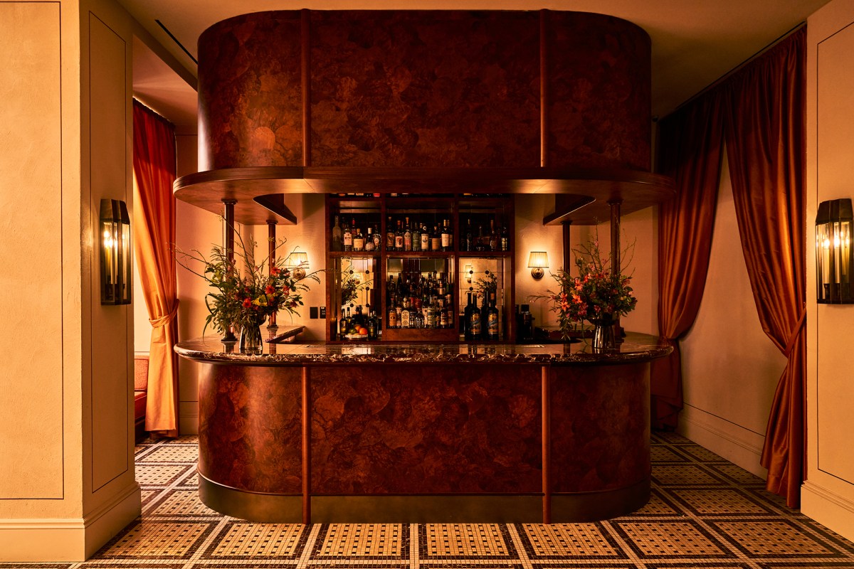 Curved art-deco bar with bottles, flowers and marble countertop in a hotel lounge