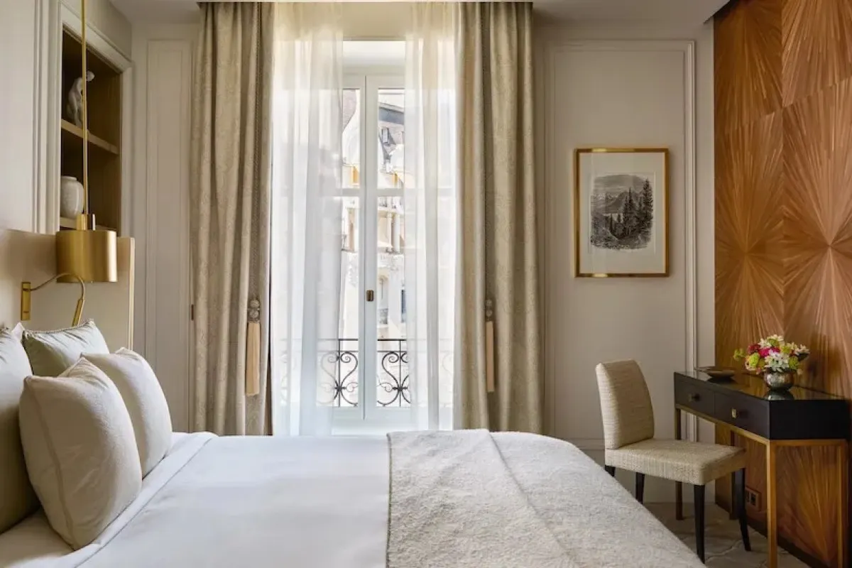 Hotel bedroom with plush bed, wood paneling, and French balcony doors