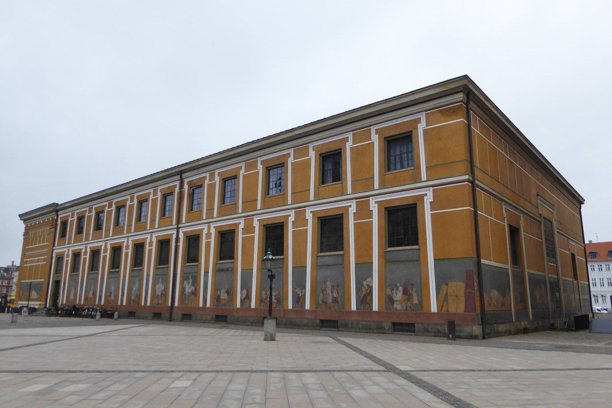 Exterior view of Thorvaldsens Museum, showing its mustard-yellow façade with painted frieze decoration.