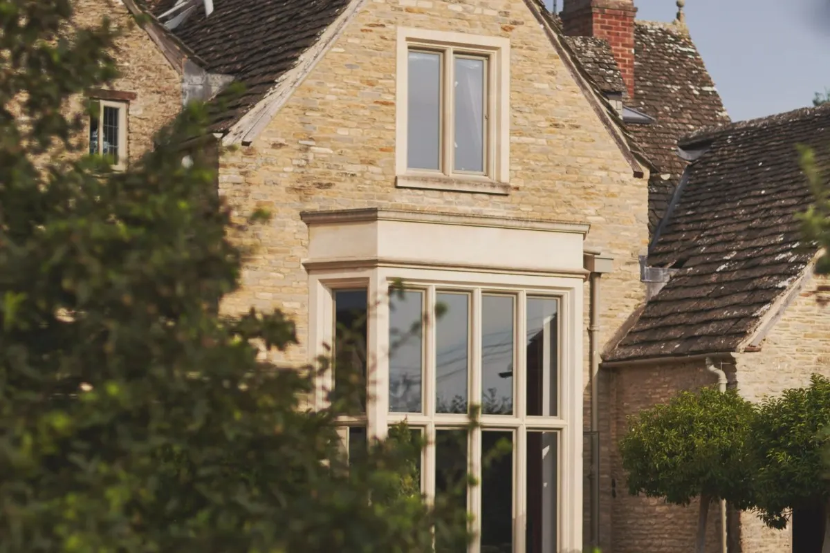 Stone gabled facade of the hotel with bay window, chimneys and climbing greenery