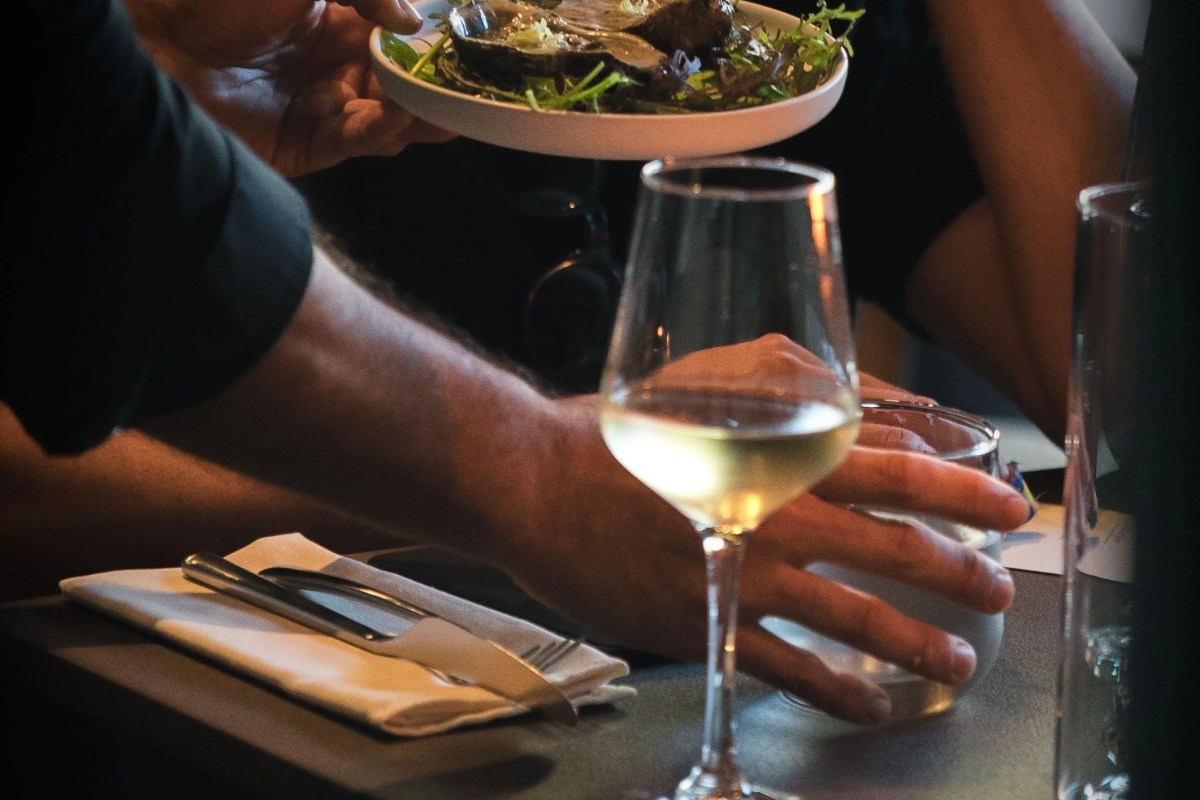 Close-up of a table setting with wine glass, cutlery, and a dish being served