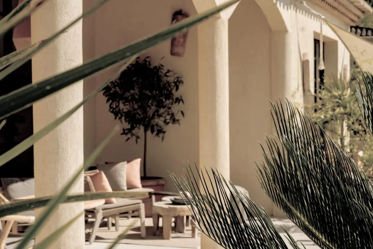 Shaded stone-arched terrace with lounge furniture along the façade of Toile Blanche hotel